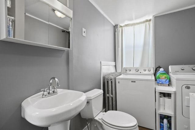 bathroom featuring sink, washer and clothes dryer, and toilet