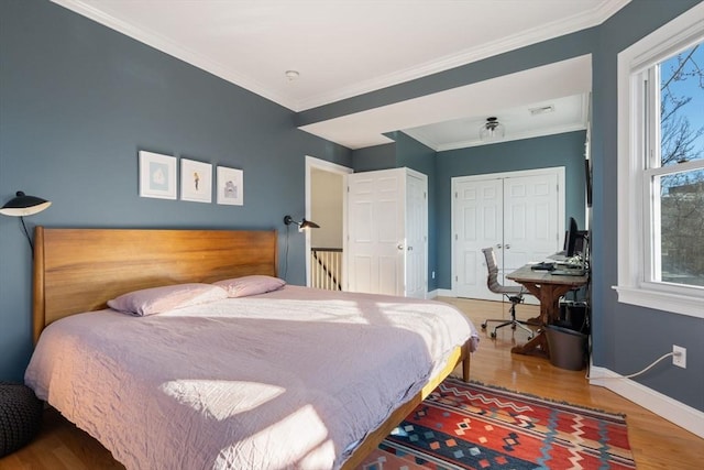 bedroom with multiple windows, crown molding, a closet, and hardwood / wood-style flooring