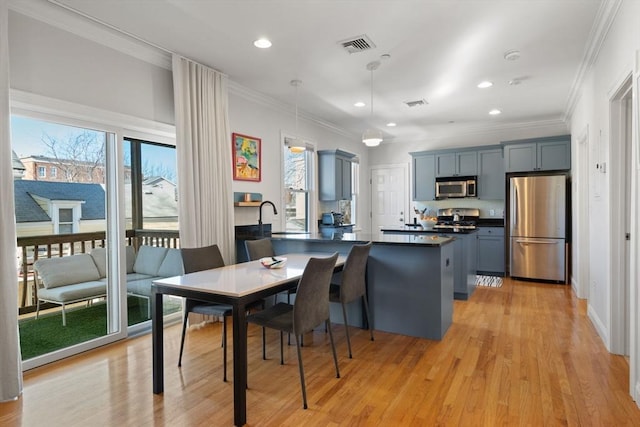 dining space with ornamental molding, plenty of natural light, and light hardwood / wood-style flooring