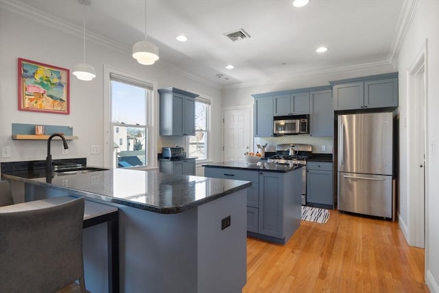 kitchen featuring crown molding, appliances with stainless steel finishes, kitchen peninsula, and hanging light fixtures