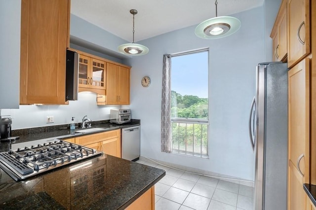 kitchen with stainless steel appliances, a sink, decorative light fixtures, glass insert cabinets, and light tile patterned flooring
