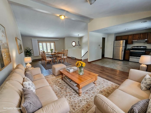 living area featuring lofted ceiling with beams, light wood finished floors, and baseboards