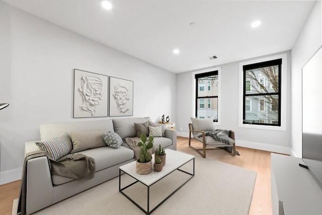 living room with recessed lighting, visible vents, baseboards, and light wood-style floors