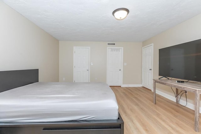 bedroom with baseboards, visible vents, and light wood-type flooring