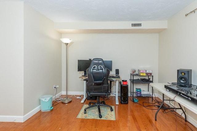 office area with visible vents, baseboards, and wood finished floors