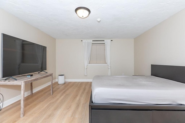 bedroom with light wood-type flooring and baseboards
