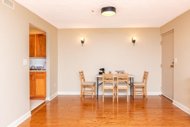 dining area featuring baseboards, visible vents, and light wood-type flooring