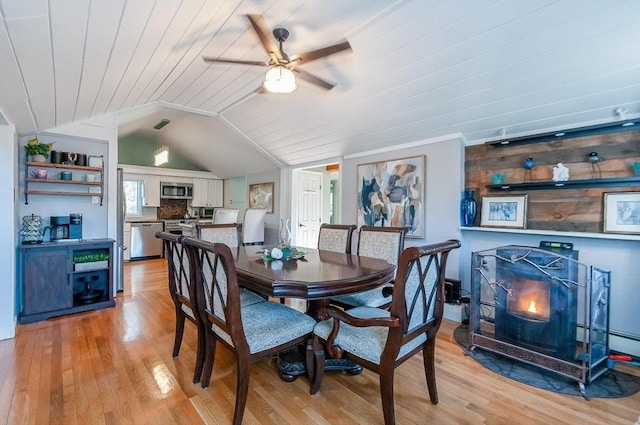 dining space featuring a wood stove, ceiling fan, wooden ceiling, vaulted ceiling, and light wood-type flooring