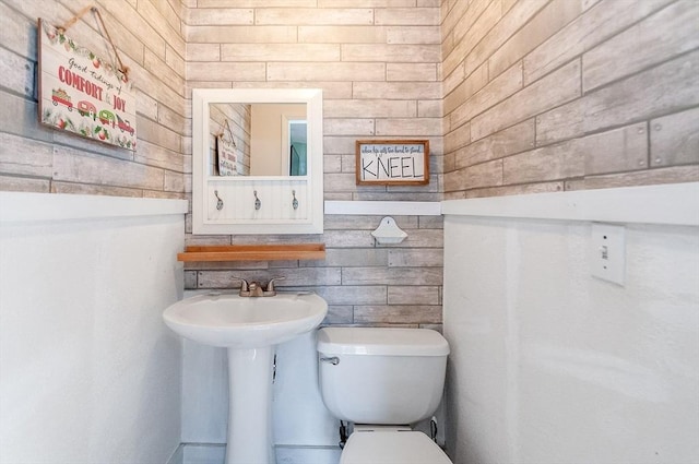 bathroom featuring toilet and wooden walls