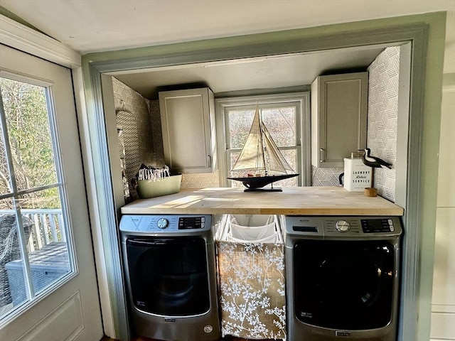 clothes washing area with washing machine and dryer and cabinets