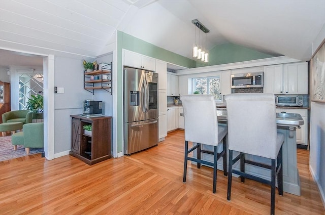 kitchen with white cabinetry, hanging light fixtures, stainless steel appliances, lofted ceiling, and light wood-type flooring