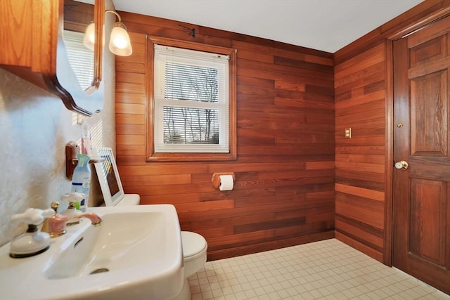 bathroom with toilet, sink, and wooden walls