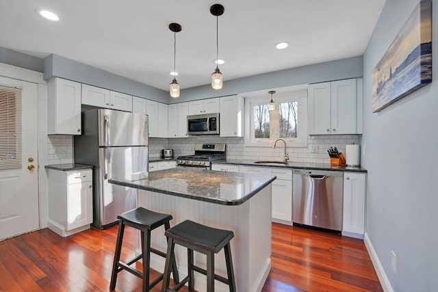 kitchen with a center island, a kitchen bar, sink, white cabinetry, and appliances with stainless steel finishes