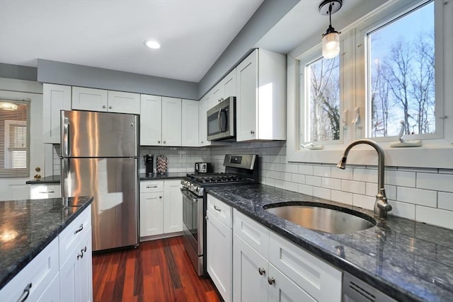 kitchen featuring appliances with stainless steel finishes, dark hardwood / wood-style floors, hanging light fixtures, white cabinets, and sink