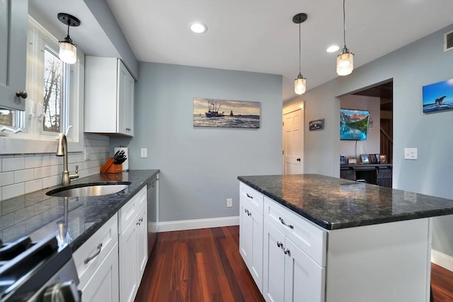 kitchen featuring sink, dark stone countertops, white cabinetry, and a center island