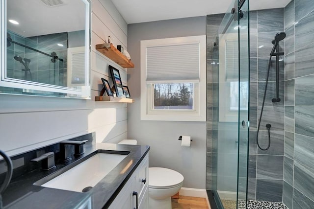 bathroom with toilet, vanity, and a shower with shower door