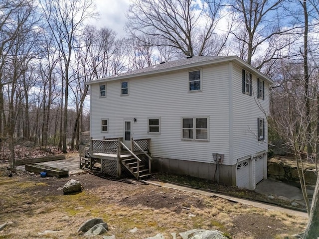 back of house with a wooden deck, driveway, and an attached garage
