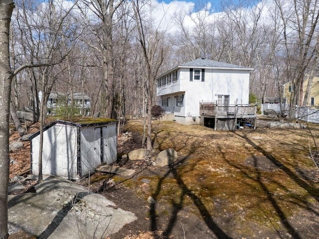 back of property with an outbuilding, a shed, and a wooden deck