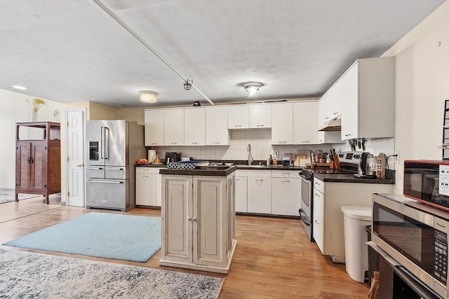 200 Market St Unit 44B, Lowell, MA 01852 - kitchen with stainless steel appliances, dark countertops, a kitchen island, light wood finished floors, and a sink