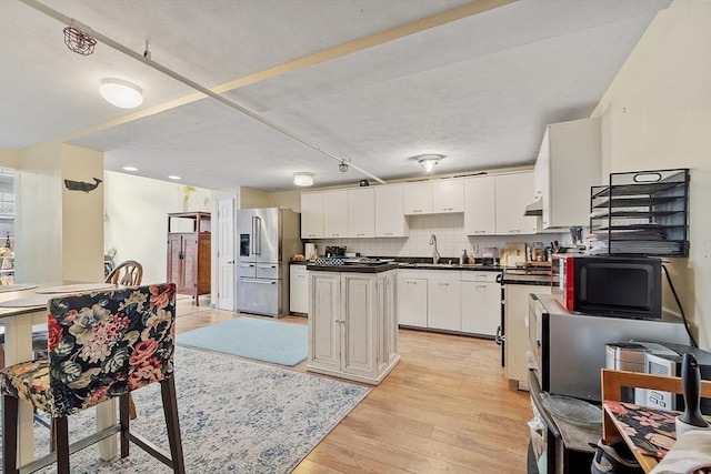 200 Market St Unit 44B, Lowell, MA 01852 - kitchen featuring high end fridge, dark countertops, white cabinets, light wood-type flooring, and under cabinet range hood