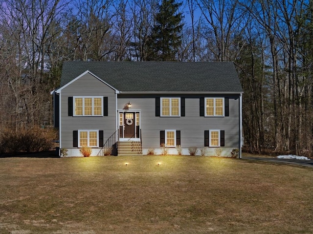 split foyer home with entry steps, a front lawn, and roof with shingles