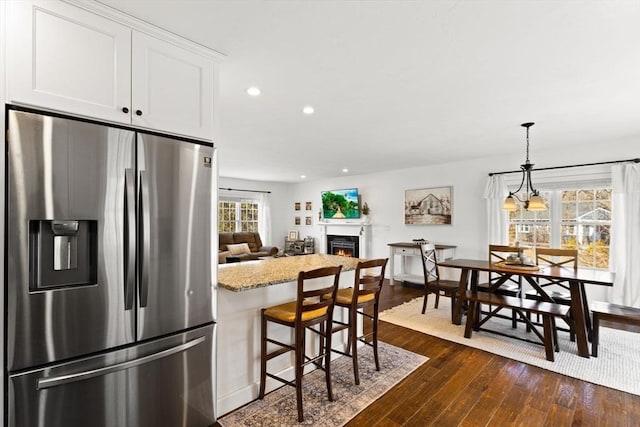 kitchen featuring recessed lighting, dark wood finished floors, white cabinetry, a lit fireplace, and stainless steel fridge