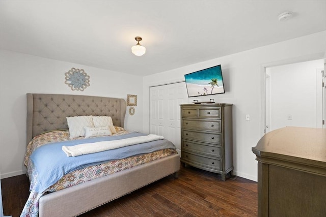 bedroom with dark wood-style flooring, a closet, and baseboards