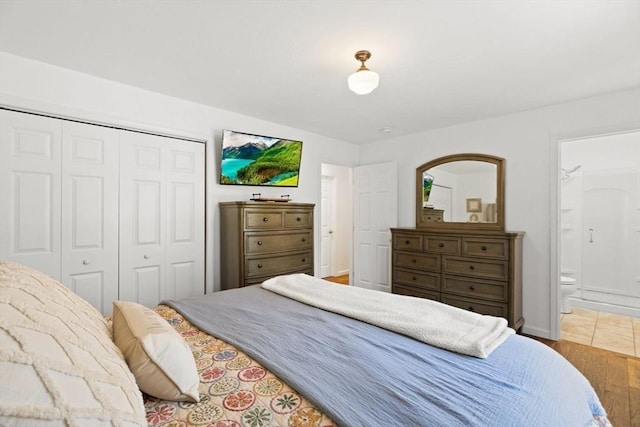 bedroom with a closet, baseboards, ensuite bathroom, and wood finished floors