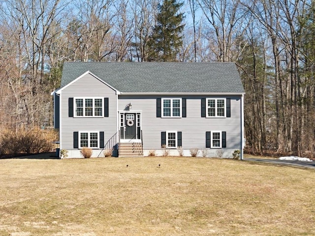 split foyer home featuring a shingled roof, a front yard, and entry steps