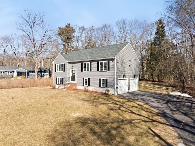 bi-level home featuring an attached garage, aphalt driveway, and a front yard