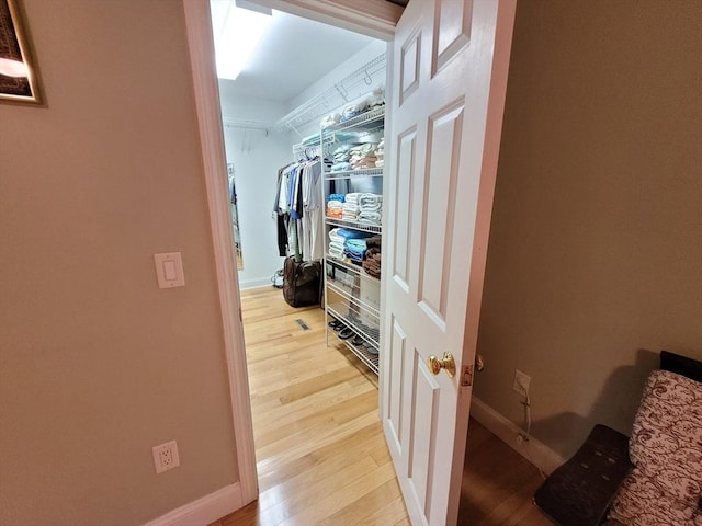 corridor featuring baseboards and light wood finished floors