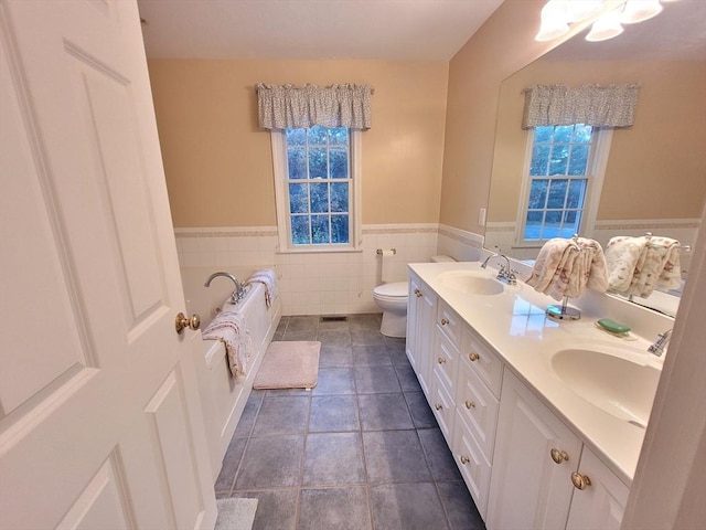 full bath featuring double vanity, toilet, wainscoting, and a sink