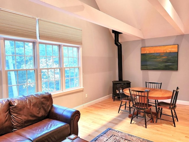 dining room with a wood stove, baseboards, and light wood-type flooring