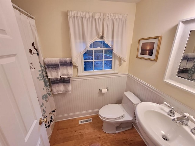 full bathroom with wood finished floors, visible vents, a sink, wainscoting, and toilet