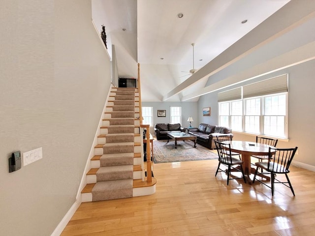 dining area featuring baseboards, stairs, lofted ceiling, light wood-style floors, and a ceiling fan