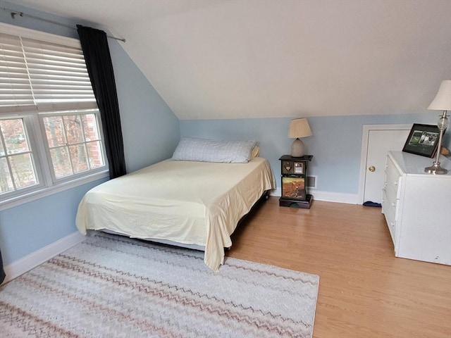 bedroom featuring baseboards, lofted ceiling, and wood finished floors