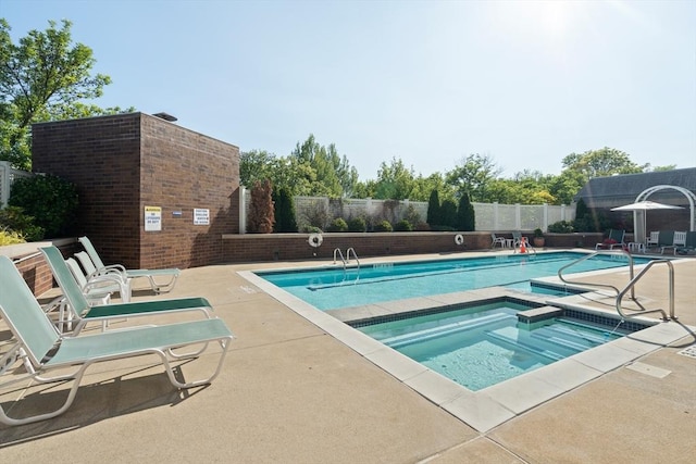 community pool featuring a hot tub, a fenced backyard, and a patio