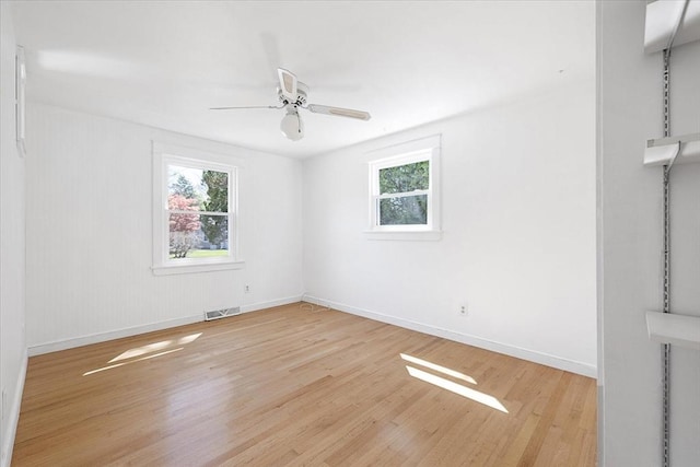 empty room featuring baseboards, ceiling fan, wood finished floors, and visible vents