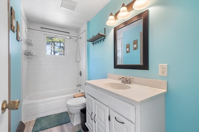 bathroom with vanity, wood finished floors, toilet, and shower / washtub combination