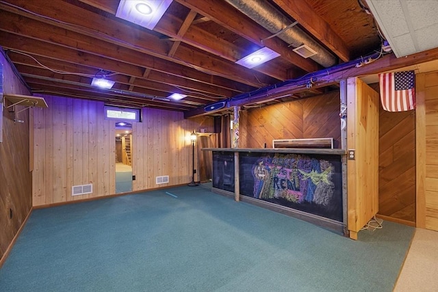finished below grade area with carpet floors, wood walls, and visible vents