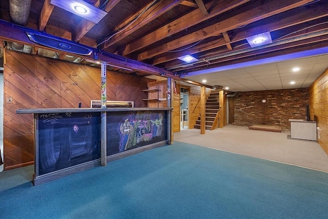 finished below grade area featuring wooden walls, carpet floors, stairs, and brick wall