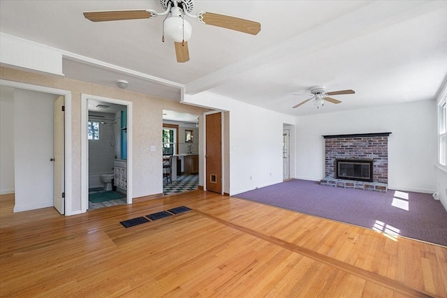 unfurnished living room with a brick fireplace, a ceiling fan, baseboards, and wood finished floors