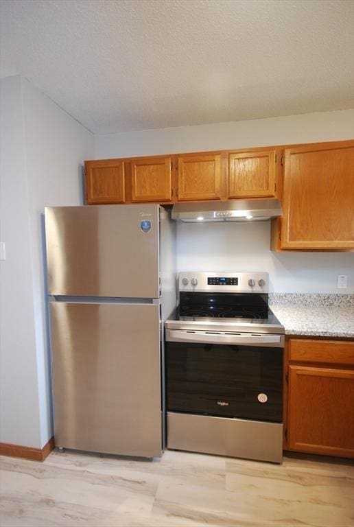 343 Chicopee St Unit 41, Chicopee, MA 01013 - kitchen with stainless steel appliances, under cabinet range hood, light wood-style floors, and brown cabinets