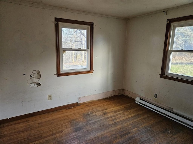 empty room with a baseboard radiator, baseboards, and wood finished floors