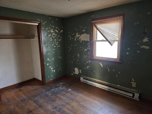 unfurnished bedroom with a baseboard radiator, wood finished floors, and baseboards