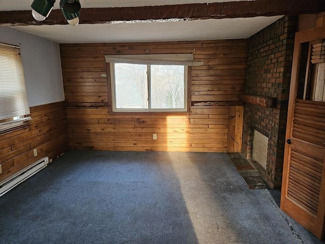 carpeted empty room with a baseboard heating unit, wood walls, and ceiling fan