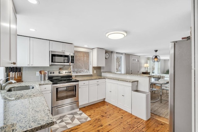 kitchen featuring appliances with stainless steel finishes, a sink, light wood-style flooring, and white cabinetry