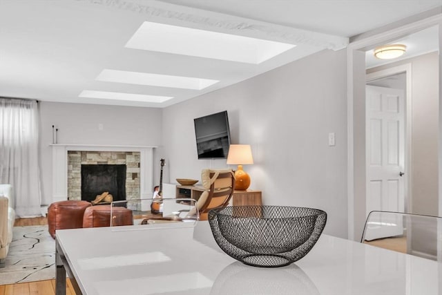 living room featuring light wood-style floors, a fireplace, and a skylight