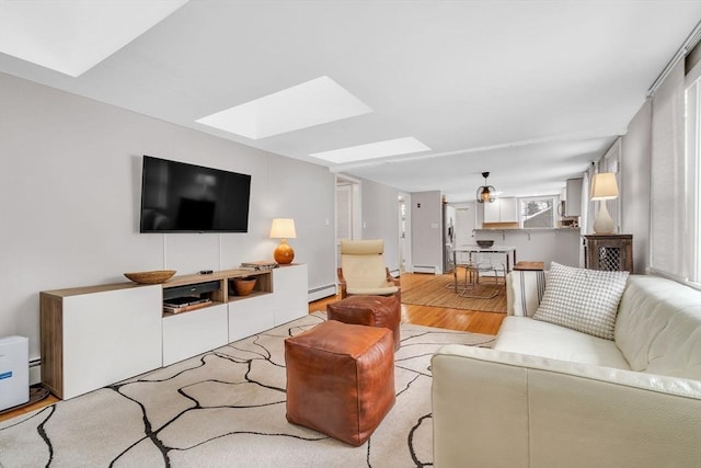 living room with light wood-type flooring, a skylight, a baseboard radiator, and baseboard heating