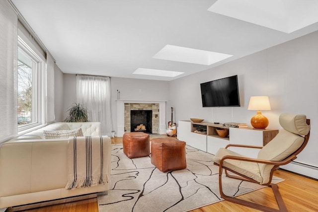 living room featuring a skylight, a fireplace, and wood finished floors